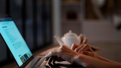 Freelance writer working remotely with laptop, coffee, and notepad in a home office setting