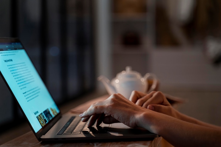Freelance writer working remotely with laptop, coffee, and notepad in a home office setting