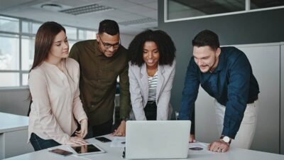 “Diverse digital marketing team working on laptops and analytics dashboards in a modern USA office, representing remote and hybrid job trends in 2025.”